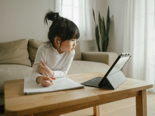 Asian daughter attending to online class from home.